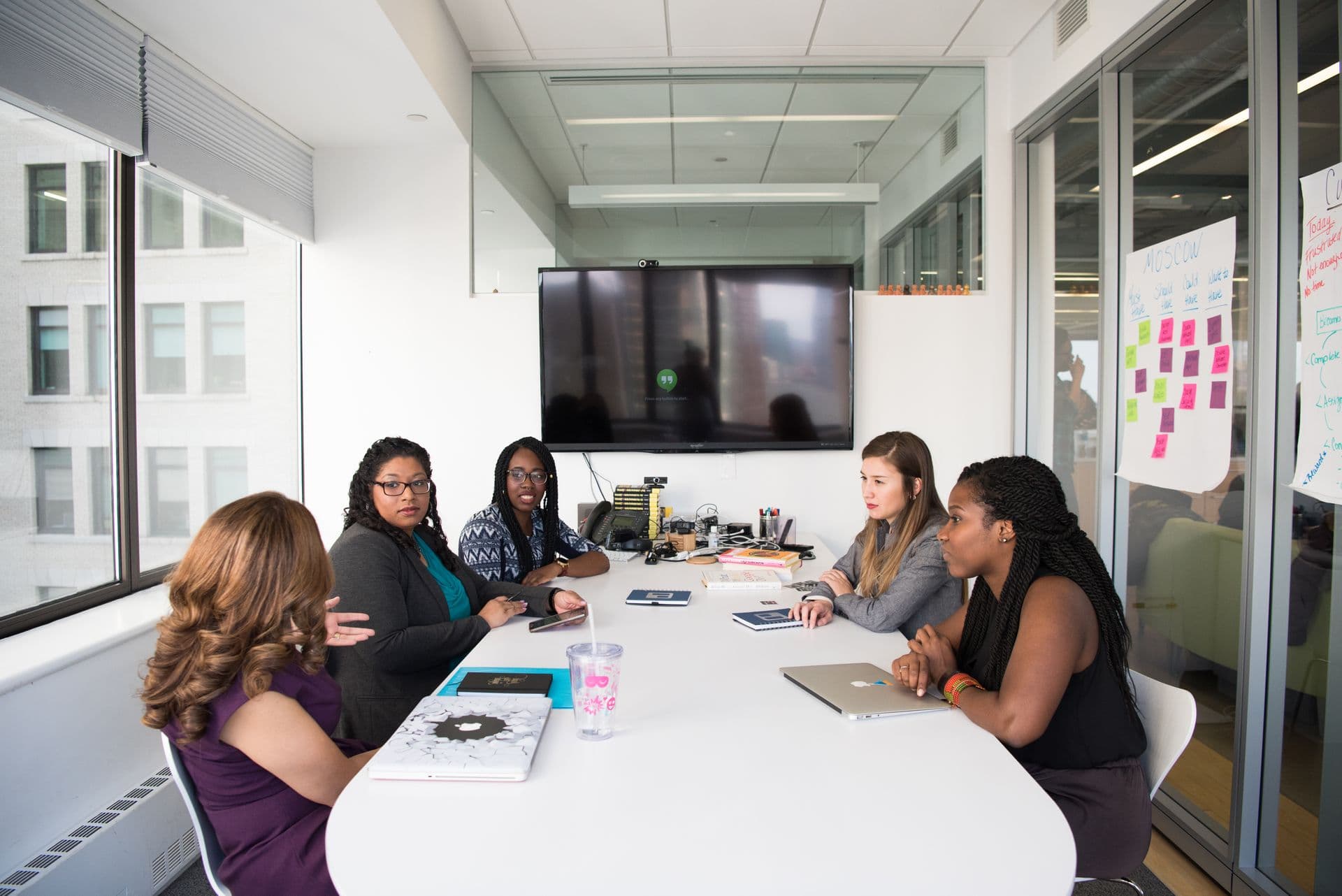 A diverse group of women directors in business attire meeting around a boardroom table
